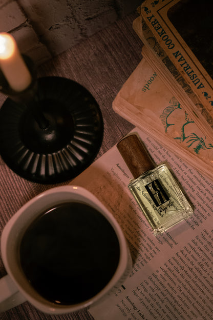 Candle, mug of coffee, and perfume bottle on a textured surface with a book.