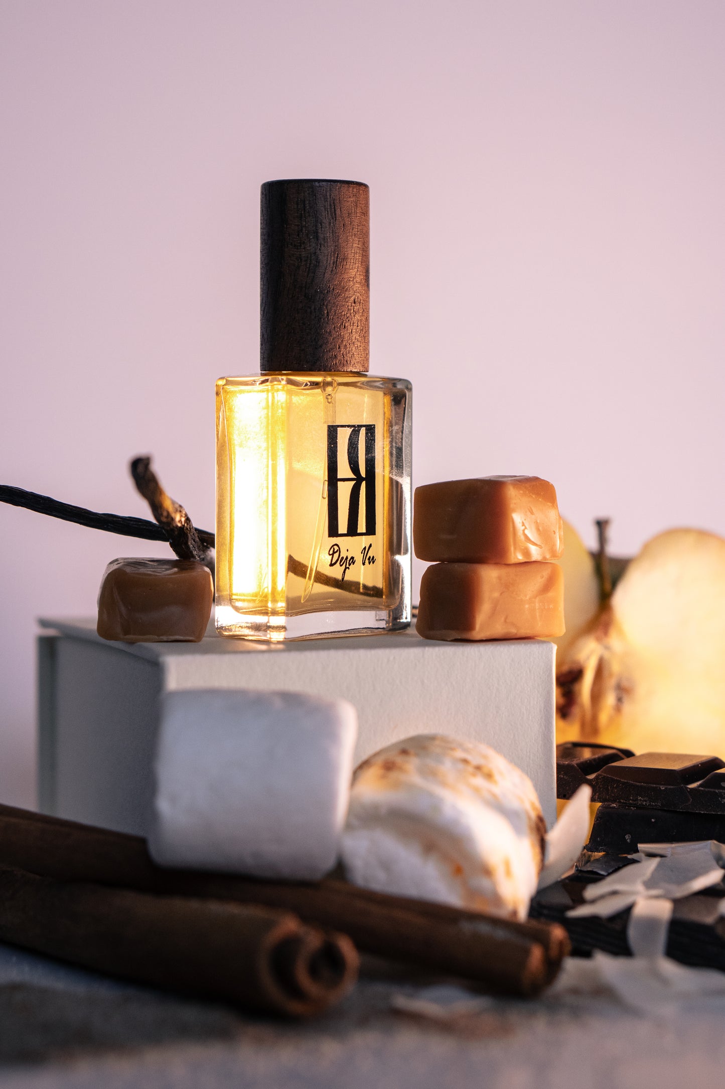 Sweet Treat perfume bottle with wooden cap on a textured surface with apple, cinnamon, marshmallows and spices